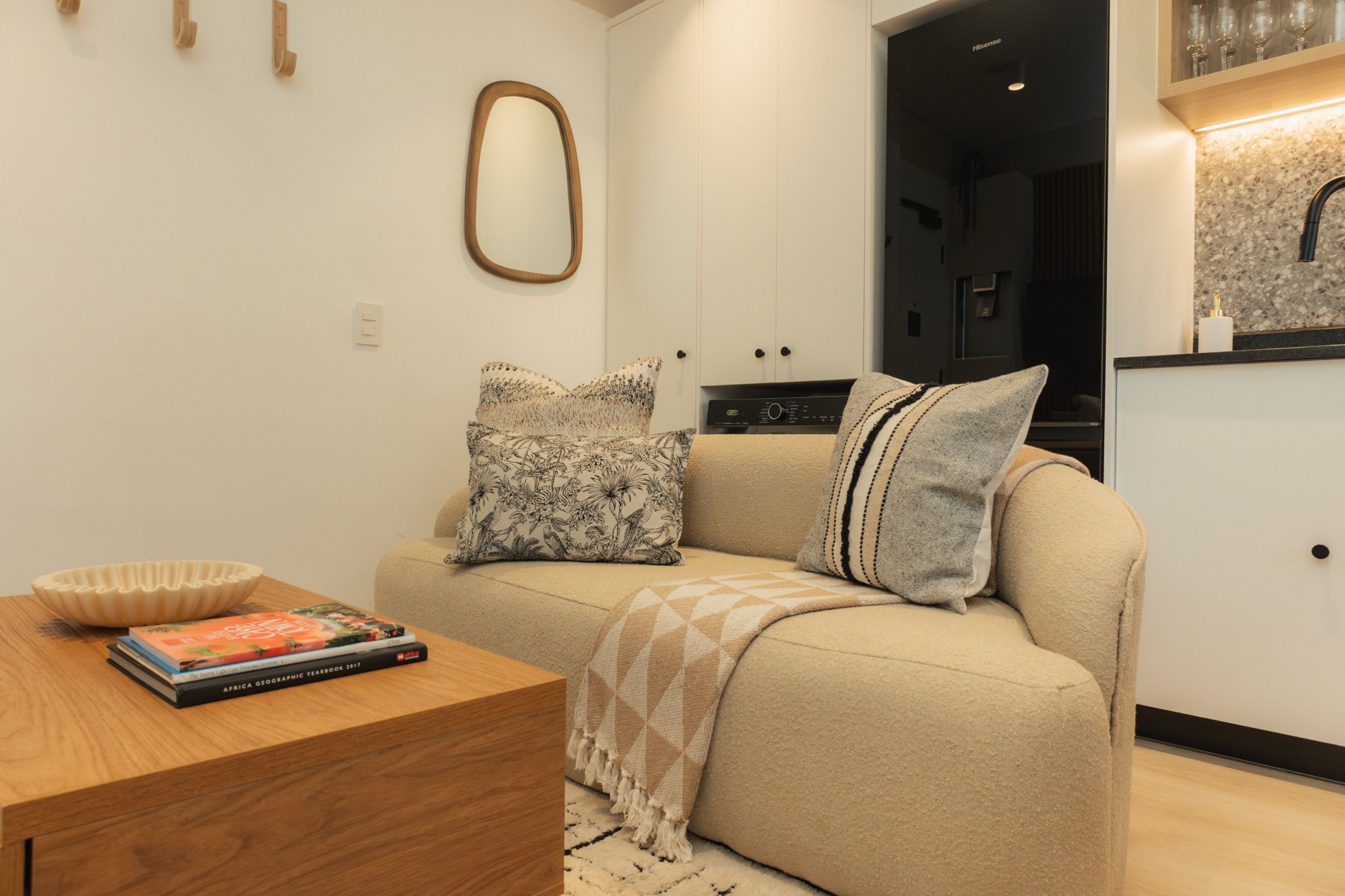 Textured cushions and a woven throw on the sofa, with art books and a ribbed ceramic bowl on the oak coffee table