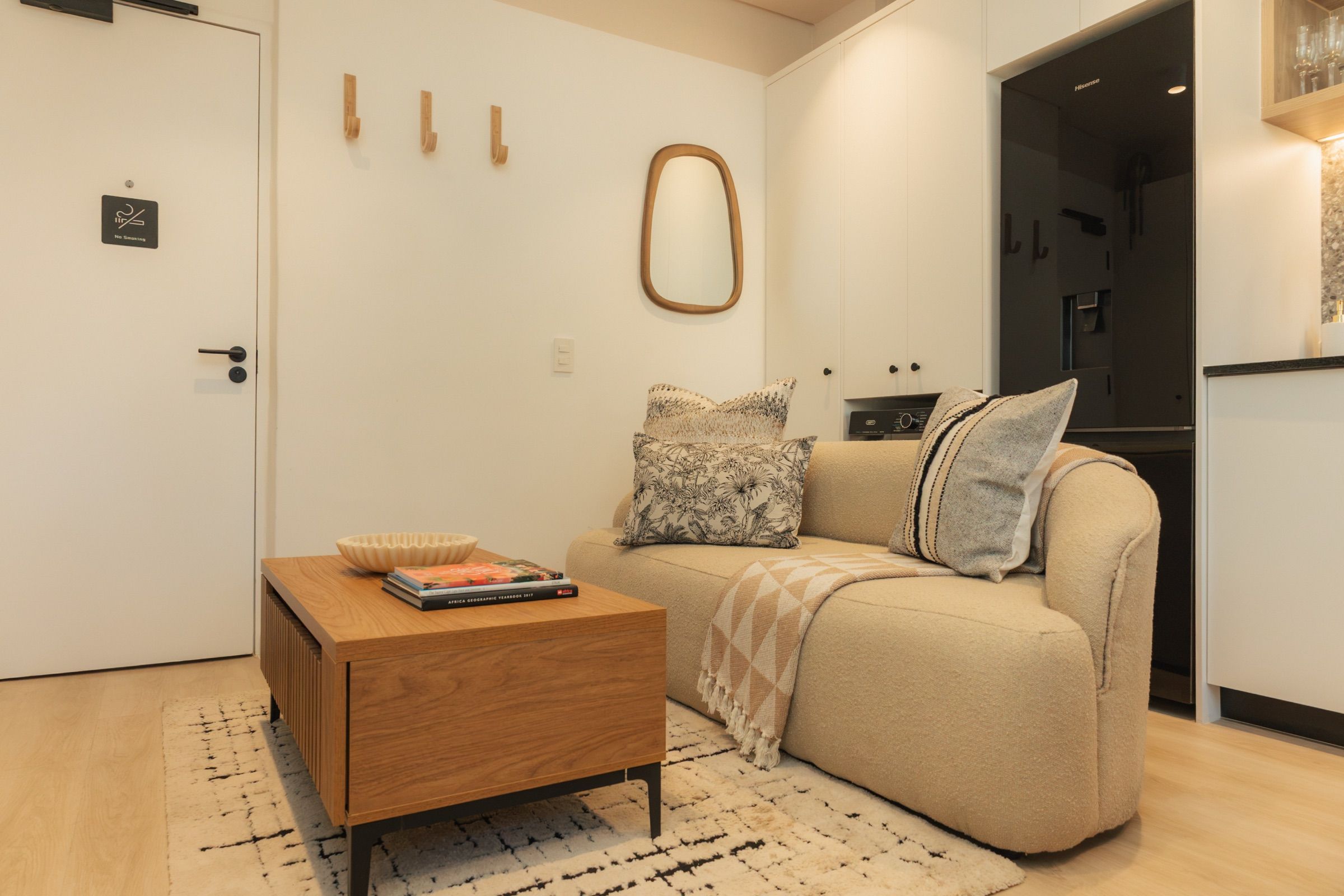 The living room with a cream boucle sofa, oak coffee table and berber rug, beside the front door and its row of oak coat hooks